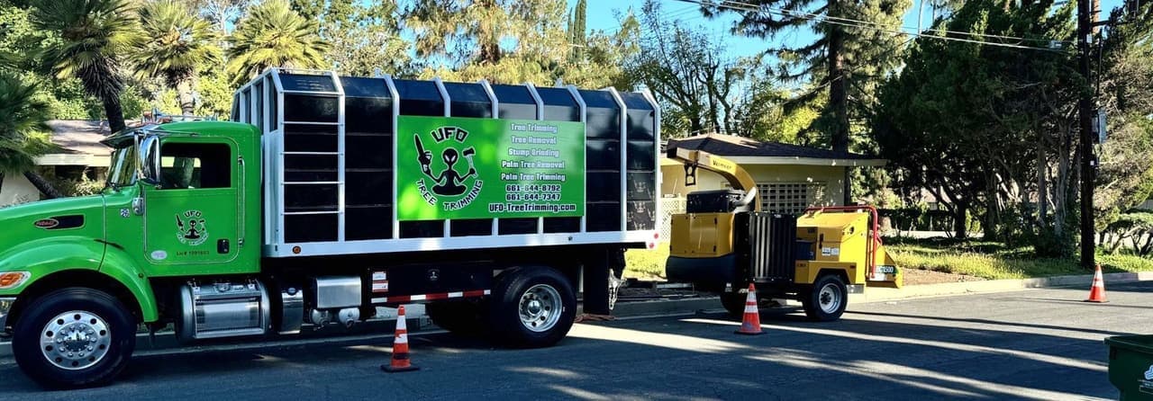 UFO Tree Trimming's chip truck and wood chipper staged behind cones on a shaded residential street
