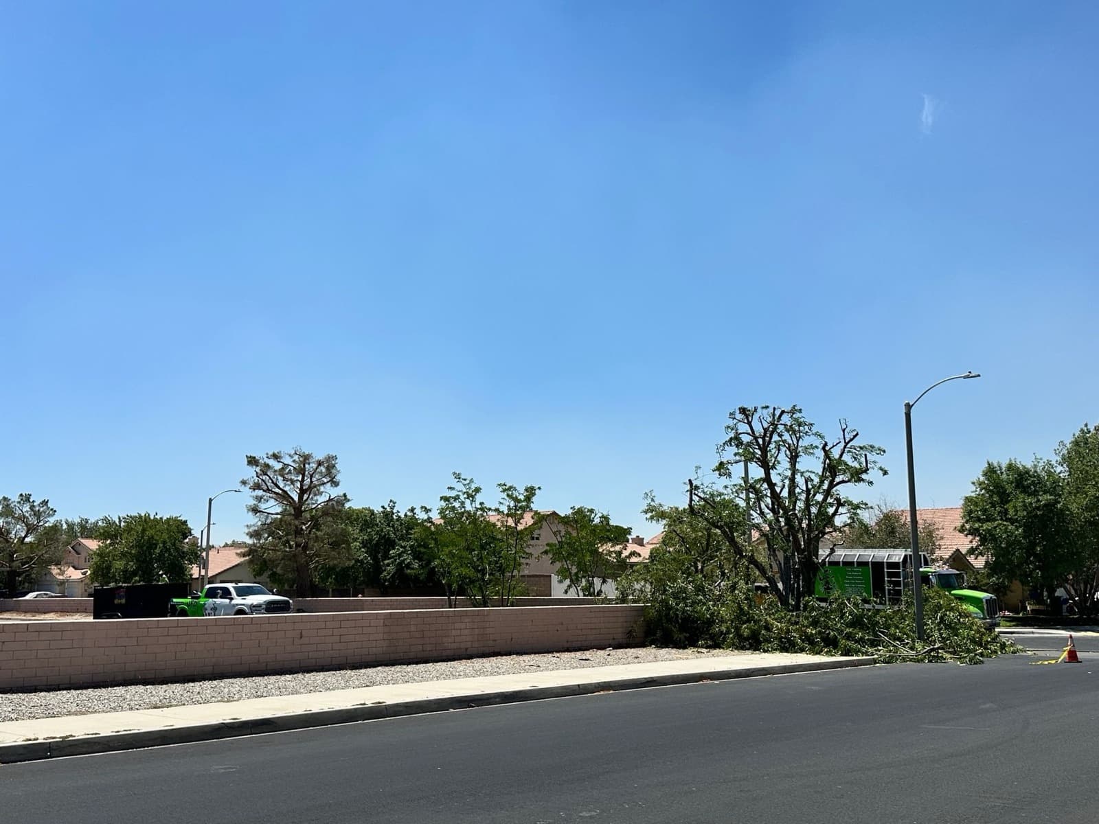 A wide Palmdale street with cleared brush and the green UFO Tree Trimming truck at work